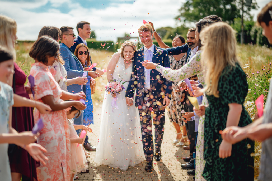 Bride and groom walking between guests throwing confetti